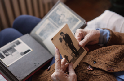 A person holding a black and white photo taken from a scrapbook. 