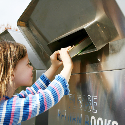 An image of a child returning a book in a large book return box