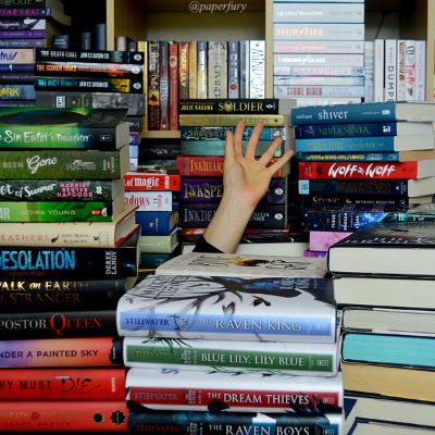 A hand sticking up from a pile of books