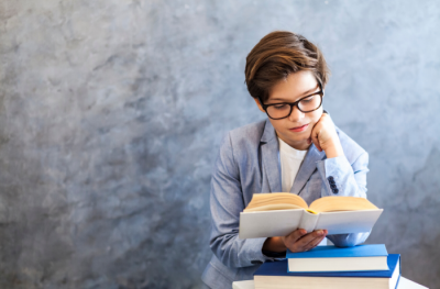 Toung teen in sportcoat reading a book