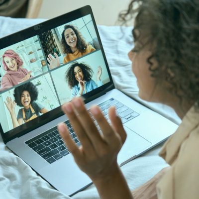 Woman waving to other women, in a virtual confernce, from her laptop