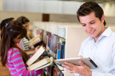 Multiple patrons browsing library shelves and a tablet