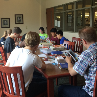 Image of teens composing comics around a table at Schlow