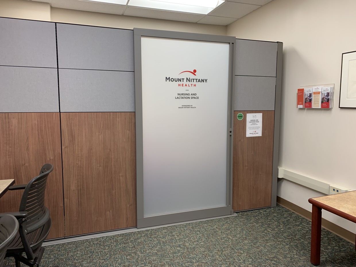 An enclosed space inside of Schlow's Children's Department with gray and brown walls with a sliding door which reads "Mount Nittany Health Nursing and Lactation Space"