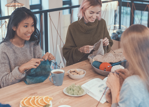 Group of people knitting around table 