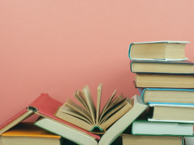 Stack of books in front of a pink background