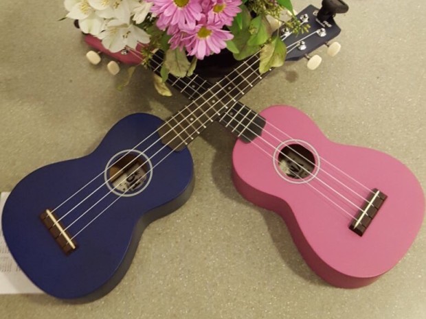 2 Ukuleles on a table with a flower